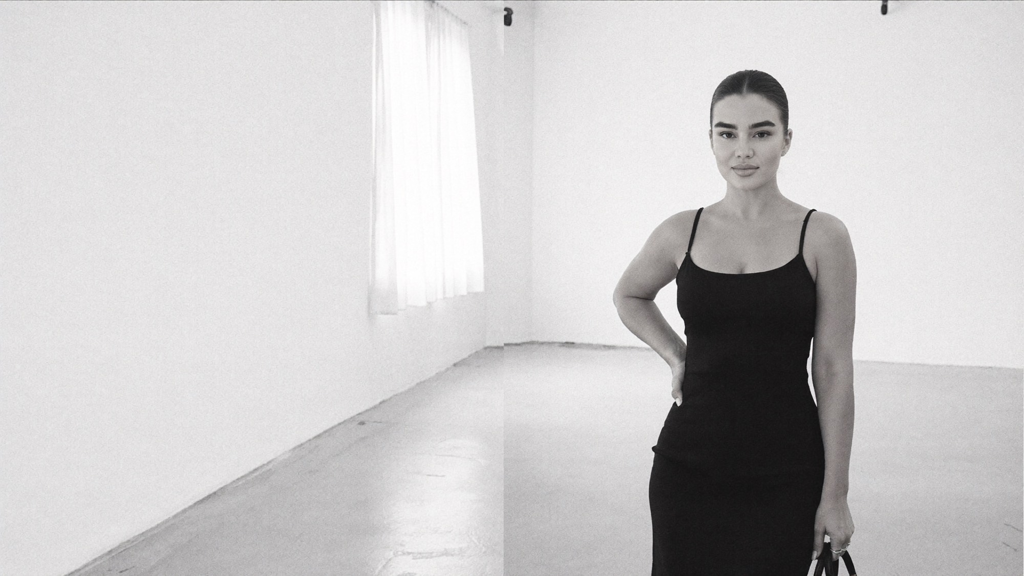 A woman standing in a white studio, entirely self-possessed.