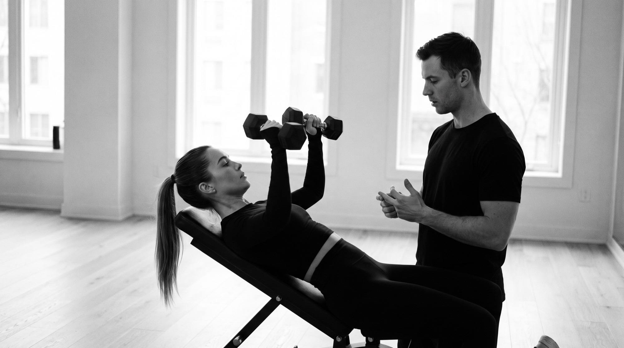 A woman training with a coach in a bright gym.